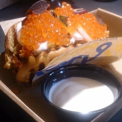 Photo of a hotdog brioche bun containing chantarelle mushrooms topped with creme fraiche and salmon roe caviar